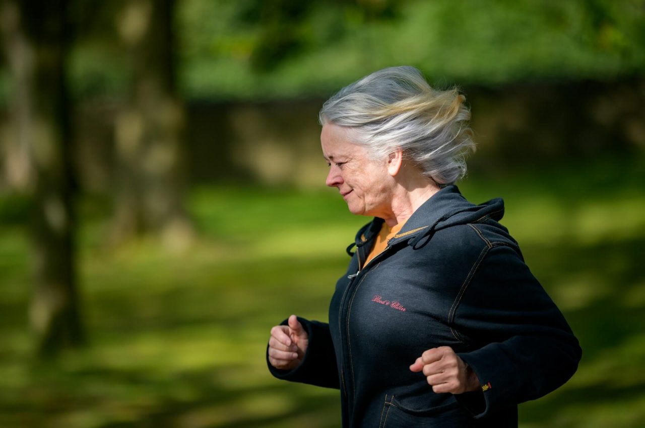 Žena běhá v přírodě jako součást zdravého životního stylu během menopauzy.